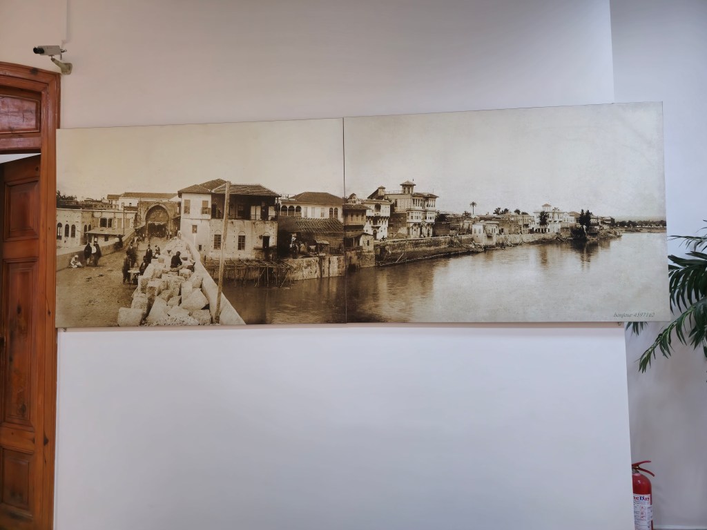 Eski bir kentin fotoğrafı, nehrin kenarındaki taş köprünün ve tarihi evlerin görüntüsü.